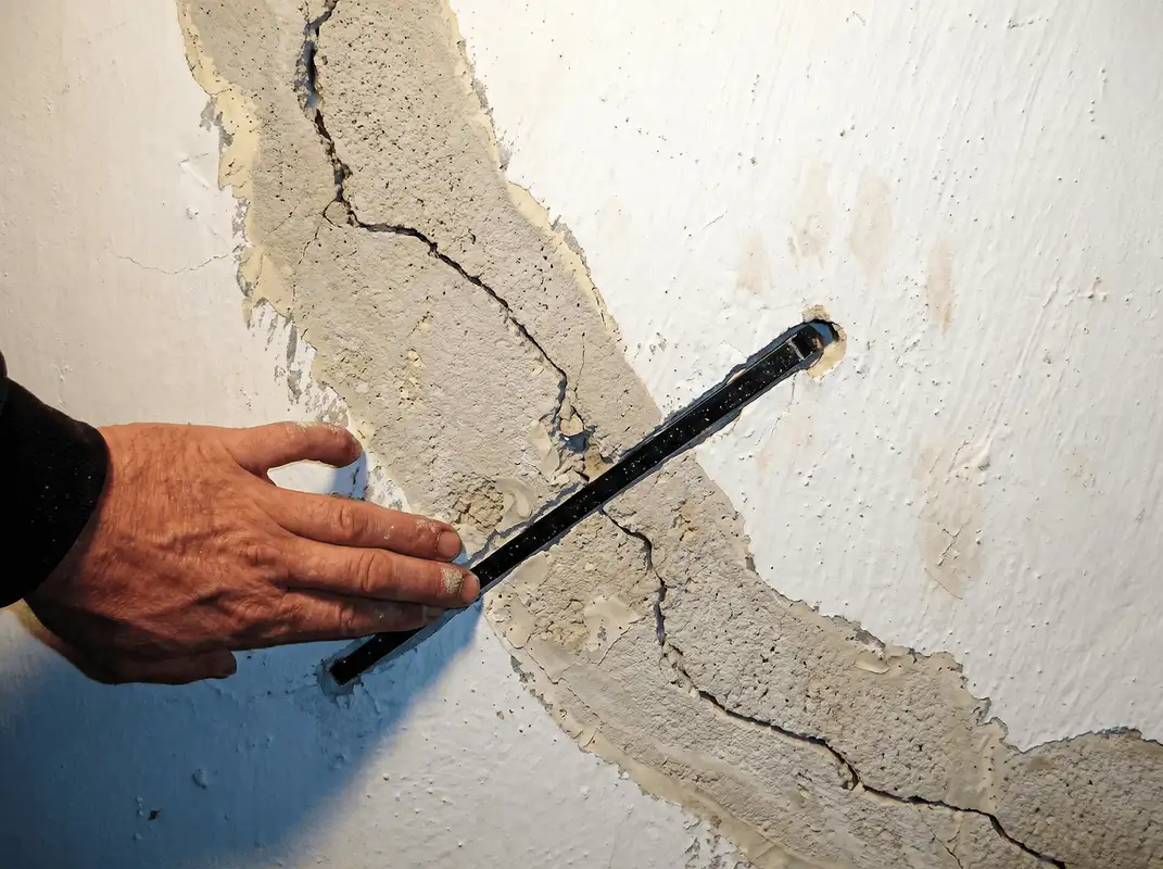 A wall with a large crack is being inspected by a professional in Cedar Rapids, IA