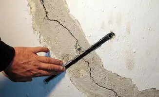 A wall with a large crack is being inspected by a professional in Cedar Rapids, IA